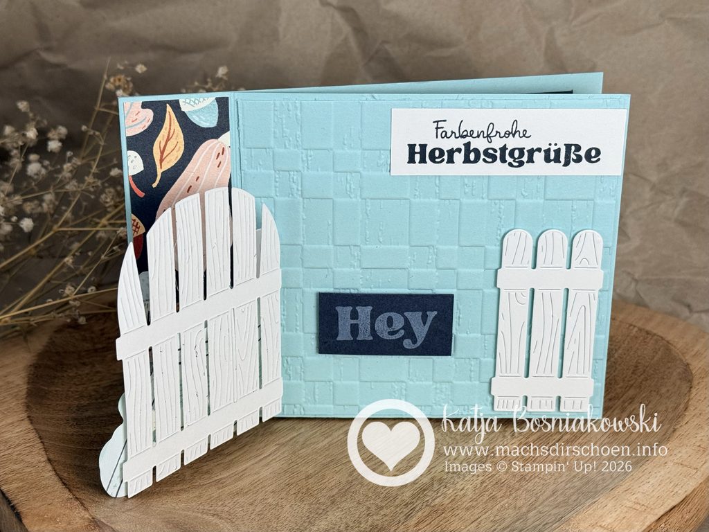 Geöffnete Buchbindekarte mit Explosionseffekt und Holzzaun im Herbstdesign